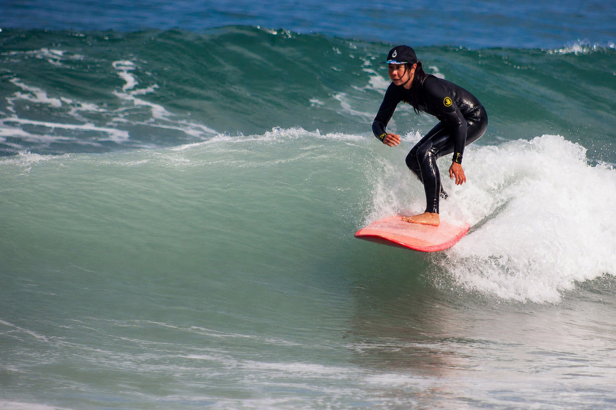 Woman surfing while wearing a Ripplix surf hat.